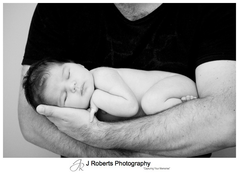 Newborn baby in her fathers arms - newborn baby portrait photography sydney
