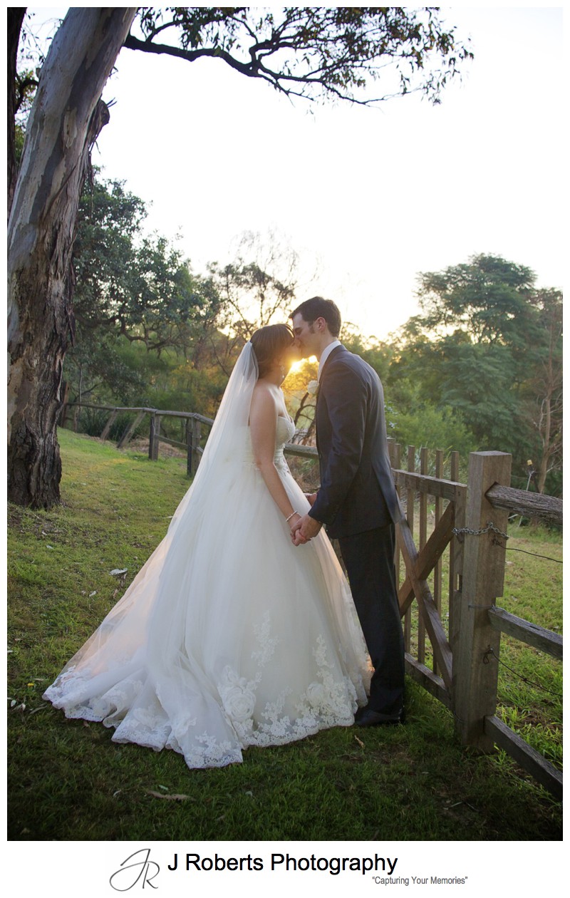 Bride and groom kissing in front of sunset - sydney wedding photographer